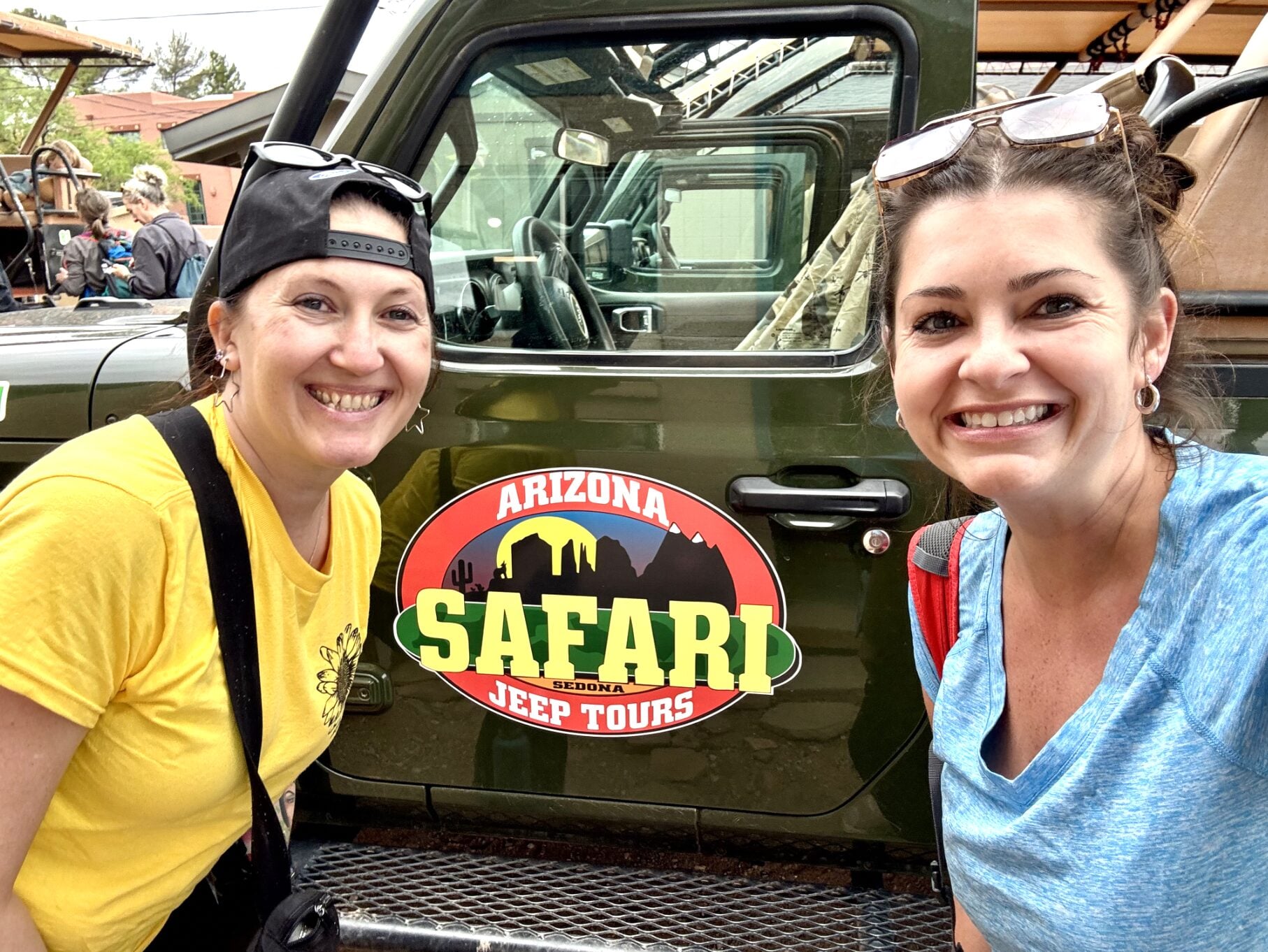 Two smiling people posing beside the Arizona Safari Jeep Tours vehicle