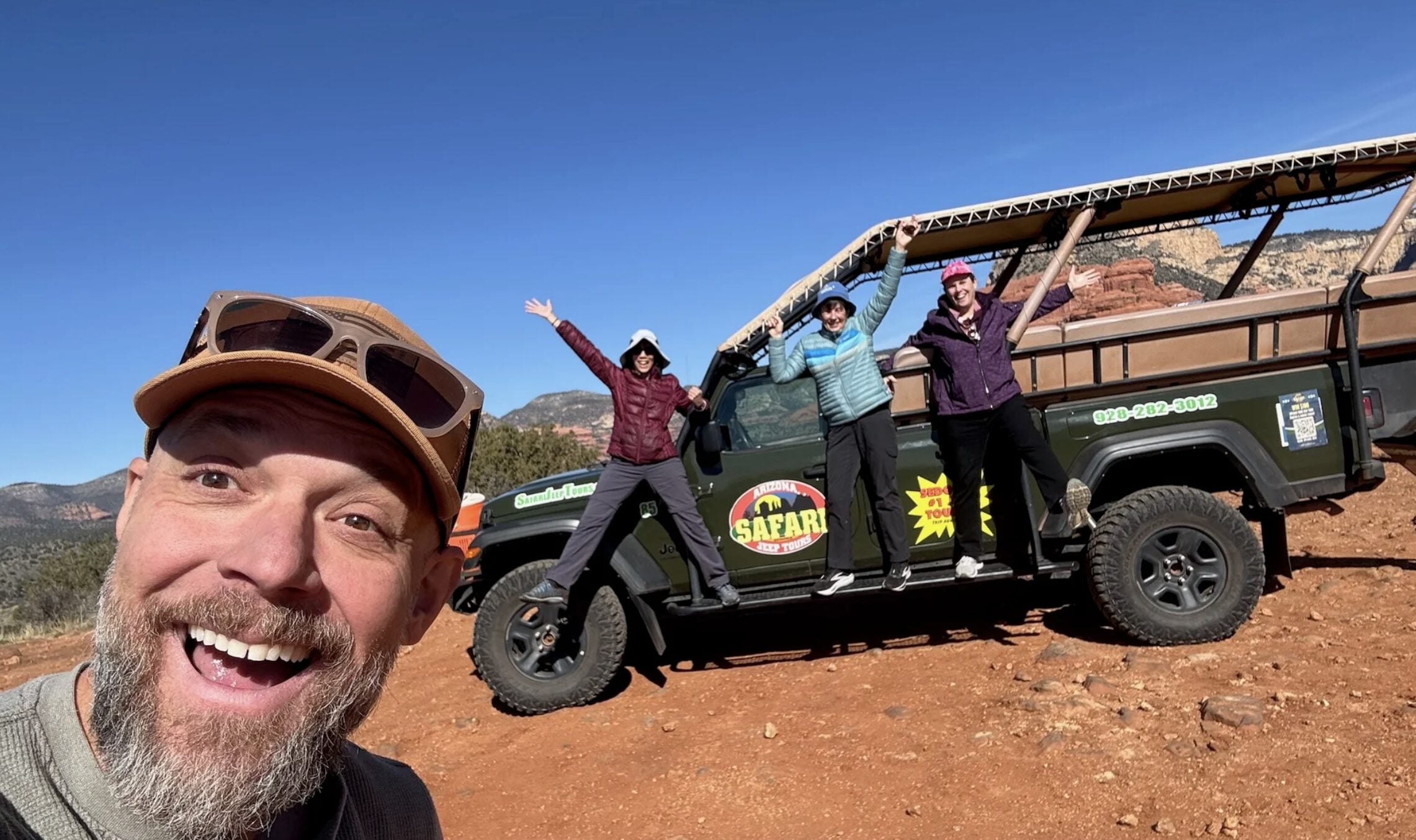 A smiling guide and three customers happily posing for a Jeep photo