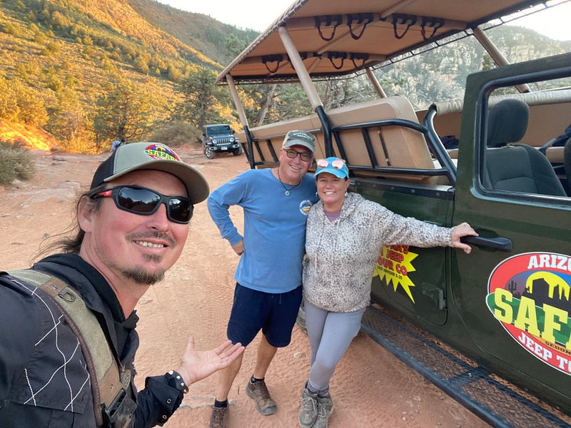 A rugged Jeep navigating through the stunning red rock formations of Sedona, with dramatic cliffs and vibrant sunset skies in the background, surrounded by lush desert vegetation and unique sandstone sculptures.