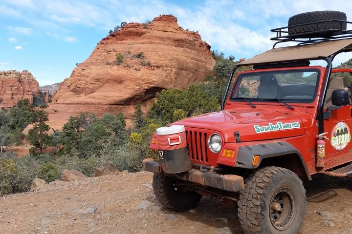 a red truck driving down a dirt road